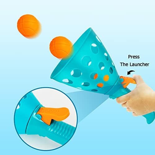 Hand holding a ball launcher toy with orange balls.