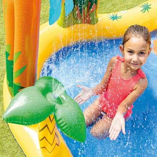 Child playing in an inflatable pool with water spraying from a green leaf.