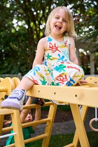 Child sitting on a wooden climbing frame outdoors