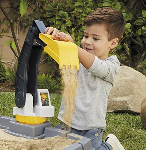 Child using a toy digger in a sandbox.