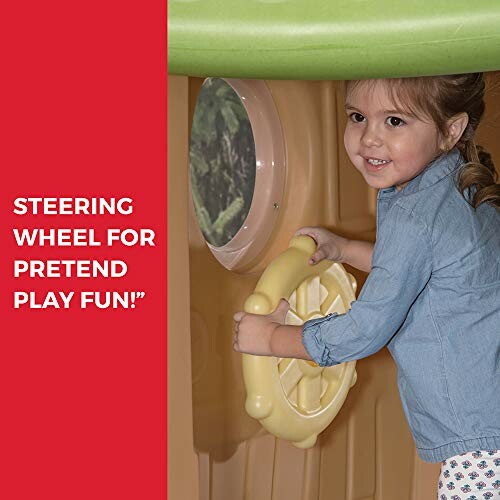Child playing with a steering wheel in a playhouse.