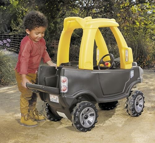 Child pushing a black and yellow toy car outdoors