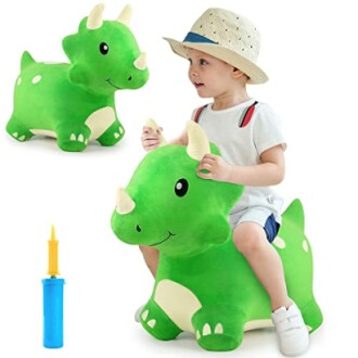 Child sitting on a green dinosaur toy with a pump.