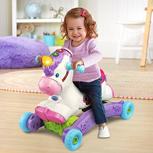 Toddler smiling while riding a unicorn toy indoors.