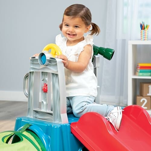 Smiling toddler playing on a toy slide indoors.