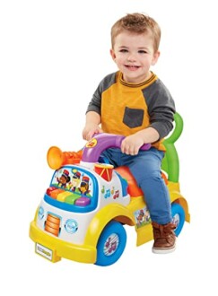 Toddler smiling while riding a colorful musical toy car.