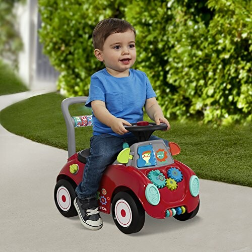 Toddler riding a red toy car outdoors