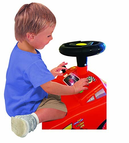 Toddler playing on a red toy car with steering wheel.