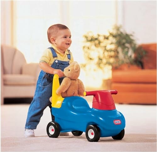 Toddler pushing a toy car with a teddy bear.