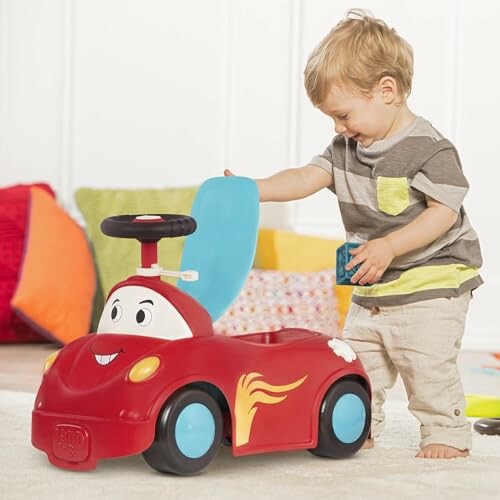 Toddler playing with a red ride-on toy car indoors.