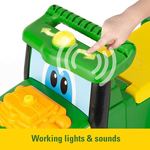 Child pressing button on green toy tractor with working lights and sounds.