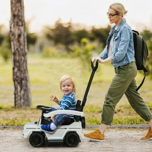 Woman pushing a child in a toy car stroller outdoors.